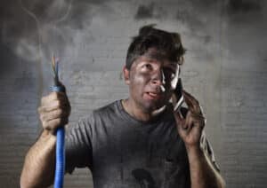 young man holding electrical cable smoking after electrical accident
