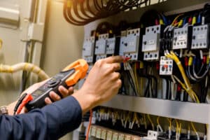 Electrician measuring voltage in electrical cabinet